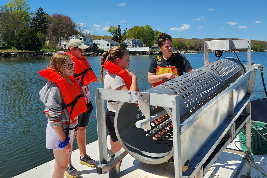3 kids with life vests listening to a woman talk